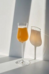 A glass of white wine, a cocktail in the rays of the sun on a light background. Celebrate and enjoy the moment. Tasting of alcoholic drinks. Glass of wine close up