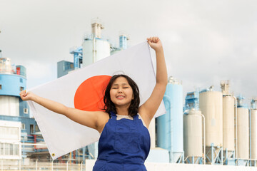 Portrait of smiling girl in construction overalls with the Japan flag on the background of a modern...