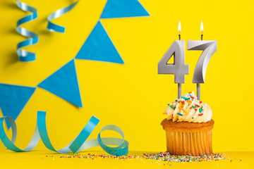 Lighted birthday candle number 47 - Yellow background with blue pennants
