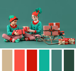 Cute little children in elves costumes with Christmas gifts and sledge on green background