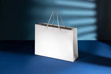 Mockup of a white paper bag without logo with handles. White package on blue background