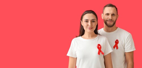 Young couple with awareness ribbons on red background with space for text. Banner for World AIDS Day