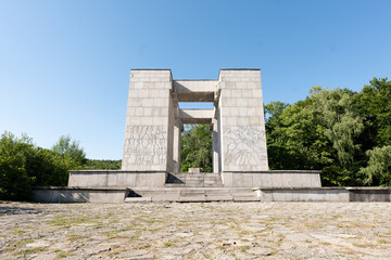Wielki kamienny pomnik w terenie zachodniej Polski o letniej porze roku na tle błękitnego nieba
