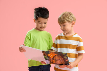 Cute little boys with book on pink background