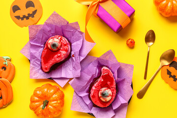 Composition with delicious fruit cakes, cookies, gift box and pumpkins for Halloween celebration on yellow background