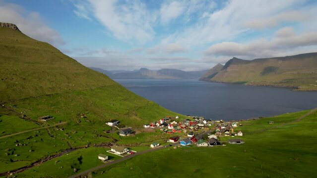 FAROE ISLANDS - JULY.16.2023 - Excellent aerial footage circling a village on the coast of Funningur in the Faroe Islands.