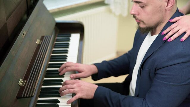An elegantly dressed man plays a song on the piano.