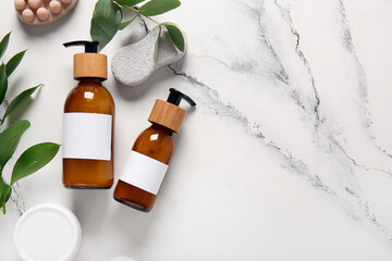 Bottles of shampoo and bath accessories on white marble background