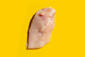 Uncooked raw chicken breast fillets on yellow  background.