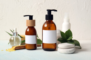 Bottles of shampoo, spa stones, sea salt and cosmetic products on white background