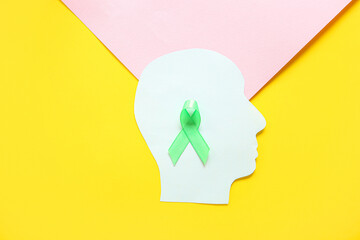 Paper human head with green awareness ribbon on color background. Mental Health Day