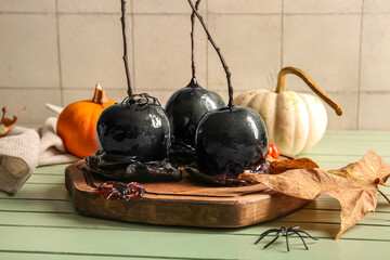Wooden board of tasty caramel apples for Halloween, spiders and scorpion on table