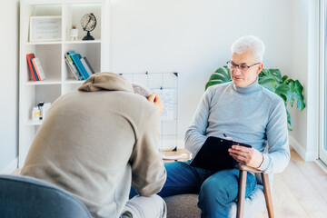 Professional psychotherapy. Male psychologist having session with male patient at mental health clinic, Taking Notes During Appointment In Office. Psychological help service. Treatment of depression