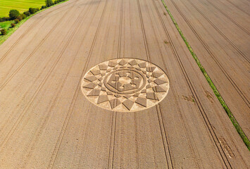 Aerial view of an intricate geometric crop circle formation in a wheat field in Wiltshire, England,...