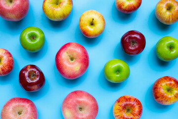 Variety of fresh apples on blue background.