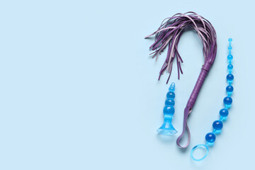 Anal plugs and whip from sex shop on blue background