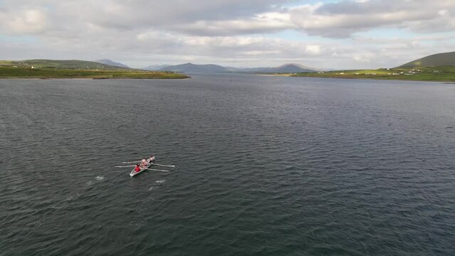 IRELAND- 8.27.2023 -Excellent aerial footage of a team rowing off the coast of Portmagee, Ireland on a cloudy day.