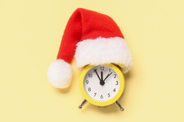 Alarm clock with Santa hat on beige background