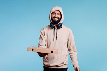 Smiling arab courier holding pizza box and looking at camera with cheerful expression. Carefree...