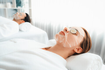 Obraz na płótnie Canvas Serene daylight ambiance of spa salon, couple customer indulges in rejuvenating with luxurious cucumber facial mask. Facial skincare treatment and beauty care concept. Quiescent