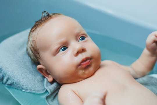 Bathing a baby in a baby bath. The first bath of a newborn baby. A baby bathes in a bath with water. Personal hygiene of a newborn