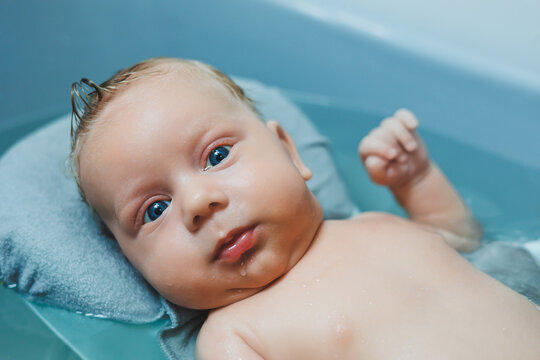 Bathing a baby in a baby bath. The first bath of a newborn baby. A baby bathes in a bath with water. Personal hygiene of a newborn