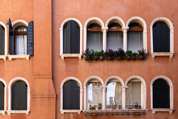 Vintage arched windows with potted plants. Orange color wall building