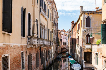 Fototapeta na wymiar Scenic canal with bridge and old buildings with potted plants in Venice, Italy