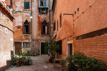 Buildings with potted plants in Venice, Italy. Charming old, weathered facade with shutters.