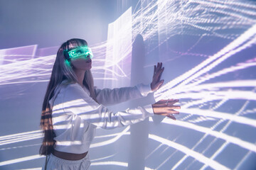 Woman in VR goggles touching wall with lights