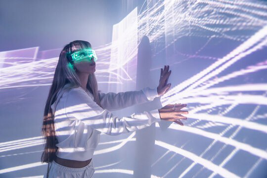 Woman in VR goggles touching wall with lights - Powered by Adobe