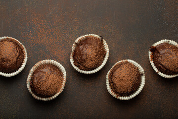 Chocolate and cocoa browny muffins top view on brown rustic stone background, sweet homemade dark...