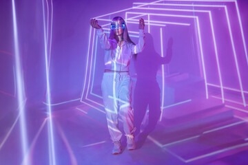 Emotionless woman in LED VR goggles experiencing virtual reality