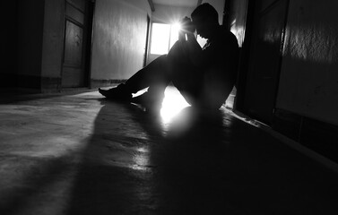 Silhouetted of sad photo. Lonely man sitting on the floor.He is unhappy and sad.He is...