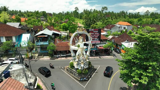 2023 - Excellent aerial footage circling cars driving past a statue of the Hindu hero Arjuna in Ubud, Bali, Indonesia.