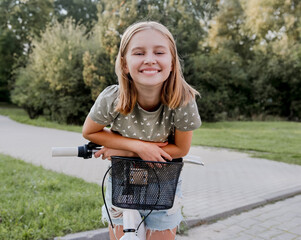 Cute preteen girl with bycicle outdoors looking at camera and smiling. Pretty child with bike at...