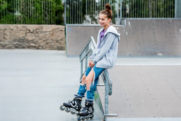 Beautiful girl roller skater riding in city park with ramp. Pretty female teenager rollerskating in...