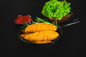 Chicken Breaded Raw Meat.Fast food.Fast cooking.Chicken nuggets with salad.Semifinished Breaded chicken nuggets from chicken fillet on a dark background with fresh herbs. Quick cooking at home.