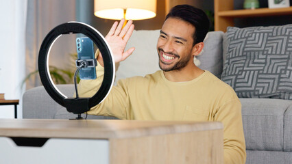 Influencer, ring light and smartphone, man wave at camera with social media, live streaming and video while at home. Content creation, communication with followers and tech, happy and subscription