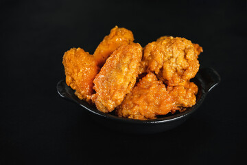 Chicken wings fried until half cooked, semi-finished product.Semi-finished chicken wings on a dark background . Half-finished. Quick cooking at home. Fast food. Breaded chicken wings.