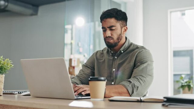 Laptop, coffee and frustrated man typing in office for online company, startup career or job in project management planning. Indian person or employee walking to his desk and working on computer