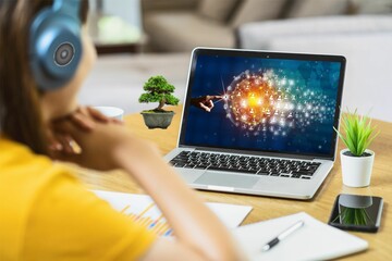 Joven mujer trabajando en su laptop. Rodeada con sus plantas en su escritorio. Utiliza auriculares....