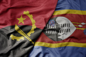 big waving national colorful flag of angola and national flag of eswatini .