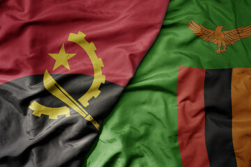 big waving national colorful flag of angola and national flag of zambia .
