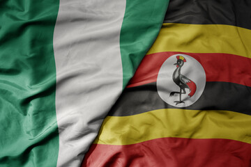 big waving national colorful flag of nigeria and national flag of uganda .