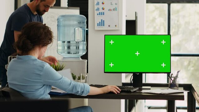 Businesswoman working at computer running isolated mockup display, sitting at office desk during work program. Employee using modern monitor with greenscreen copyspace layout at job.