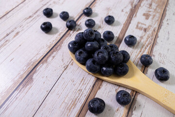 Blueberries on a Spoon lying on Blue Wood Background