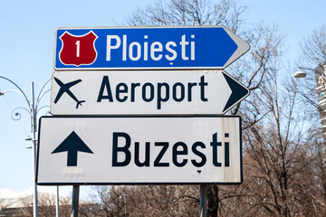 Fototapeta premium Selective blur on a romanian roadsign in the streets of bucharest indicating the directions to Ploiesti and Buzesti and the way to the Bucharest Airport.