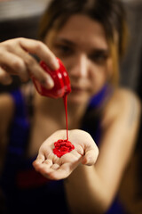 Female artist pouring red color from a bottle on her hand.