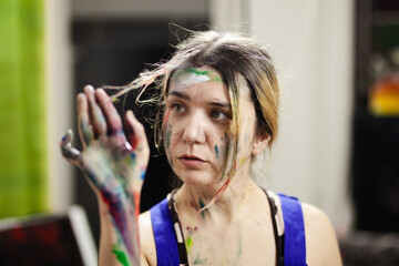 Portrait of a female artist. Girl with clumsy clorful painted face.